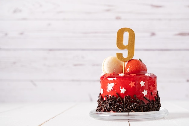 O número nove em um bolo de aniversário vermelho sobre um fundo claro