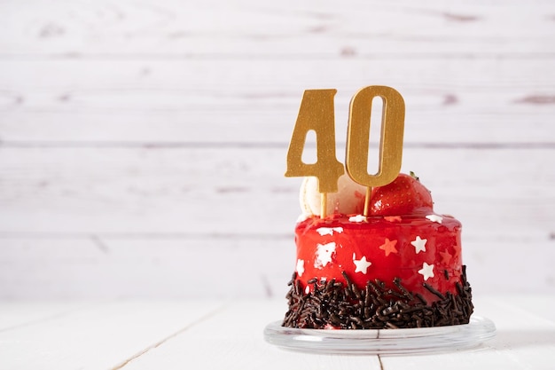 O número quarenta em um bolo de aniversário vermelho sobre um fundo claro