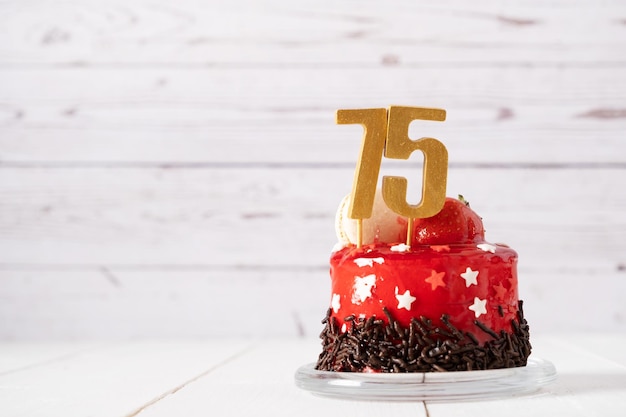 O número setenta e cinco em um bolo de aniversário vermelho sobre um fundo claro