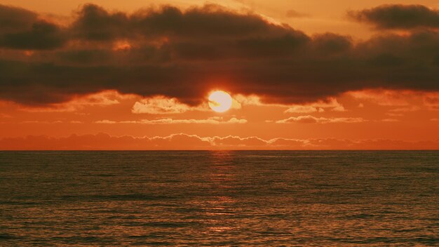 O oceano ao pôr-do-sol direito queimando pôr- do-sol acima do mar o sol está a pôr-se sobre o mar ou o oceano