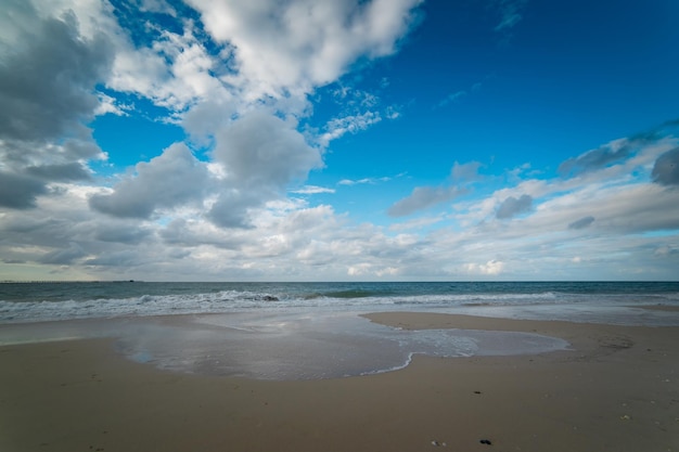 O Oceano Índico banha suavemente a costa de areia branca da bela praia perto de Busselton South Western Australia protegida por Geographe Bay em uma tarde de céu azul e nuvens brancas no início do verão