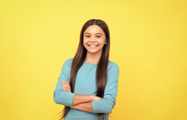 O olhar bonito do retrato da cara da menina da criança no fundo amarelo expressa emoções positivas