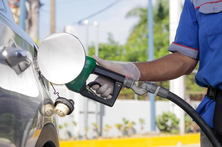 O operador da estação de serviço segura a mangueira de combustível para depositar gasolina no veículoxA