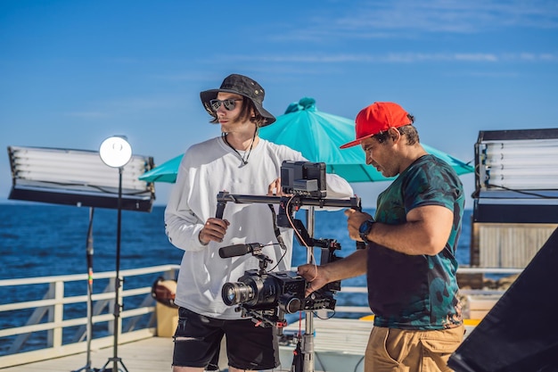 O operador da Steadicam e seu assistente preparam a câmera e o estabilizador de 3 eixos para uma filmagem comercial