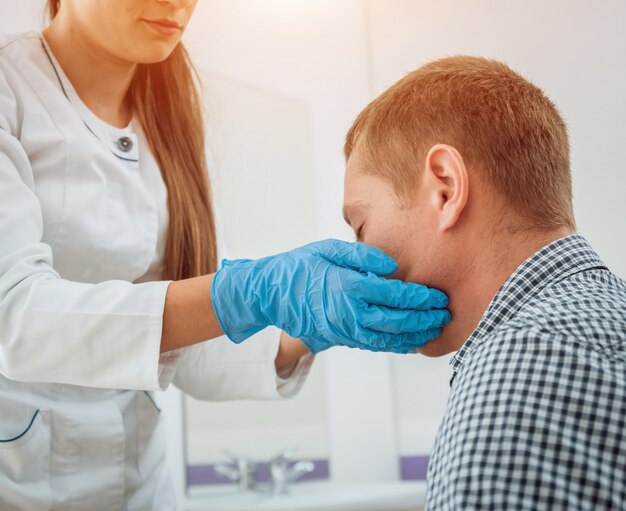 O otorrinolaringologista examina a garganta do homem.