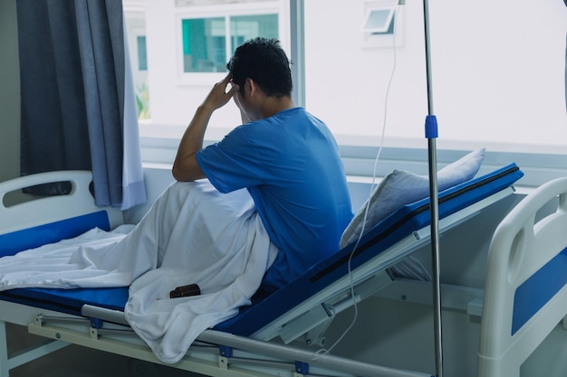 O paciente sentou-se na cama e olhou pela janela do hospital sozinho e teve estresse, tédio, solidão, ansiedade Cuidados de saúde e assistência médica