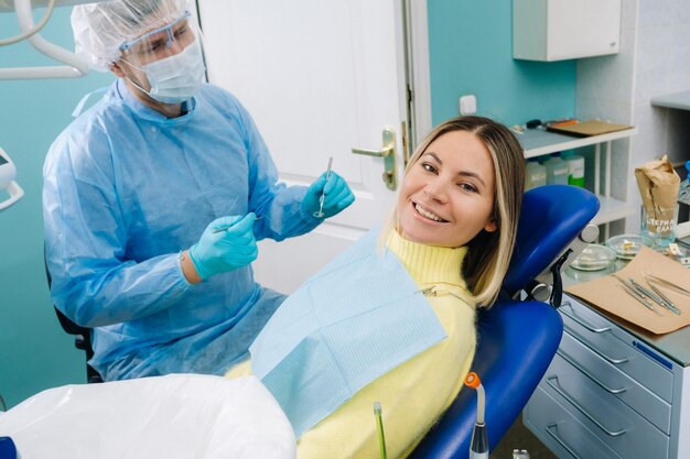 O paciente sorri na cadeira do dentista em uma máscara protetora e instrumento antes do tratamento no consultório odontológico