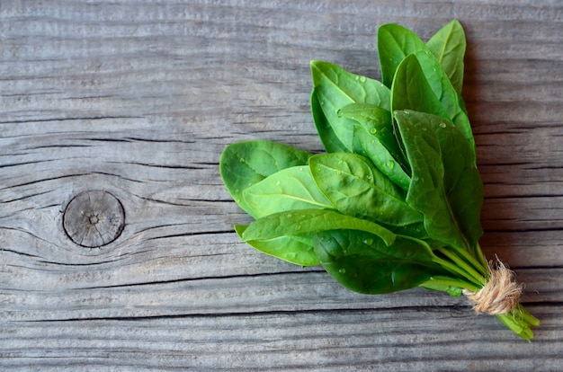 O pacote orgânico verde fresco dos espinafres sae na tabela de madeira velha Comer saudável, desintoxicação, conceito do ingrediente de dieta.