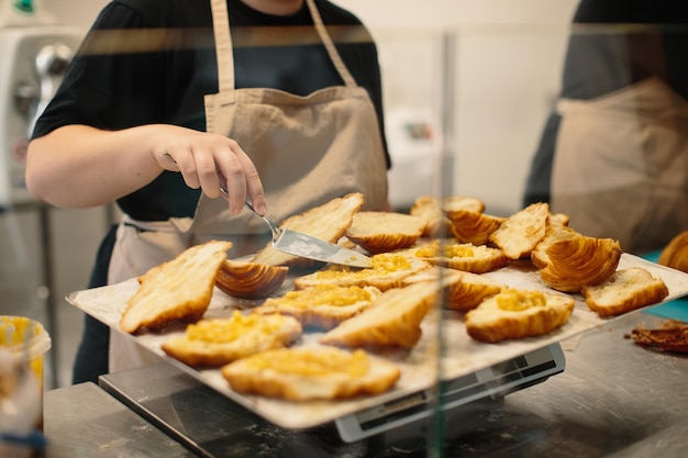 O padeiro adiciona geleia aos croissants Conceito de cozimento de croissants