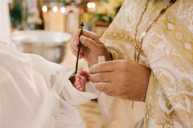 O padre esfrega as pernas do bebê na igreja ortodoxa