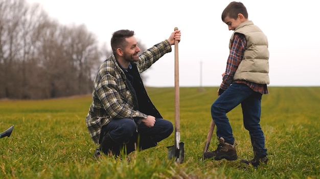 O pai com seu filho plantando uma árvore no campo