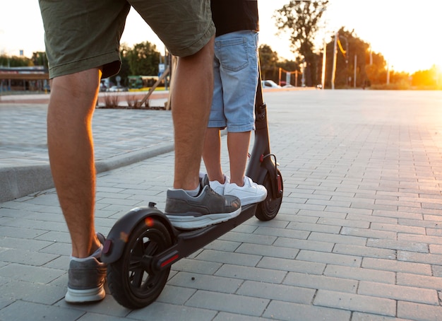 O pai dirigindo a scooter elétrica com o filho pelo estacionamento vazio