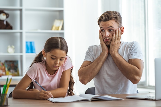 O pai e uma filha fazendo lição de casa na mesa