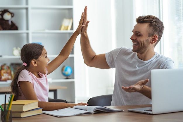 O pai e uma filha sentados à mesa e gesticulando