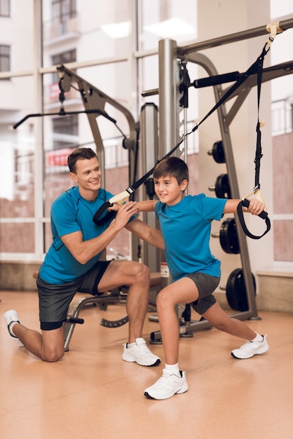 O paizinho e o filho novo exercitam no gym.