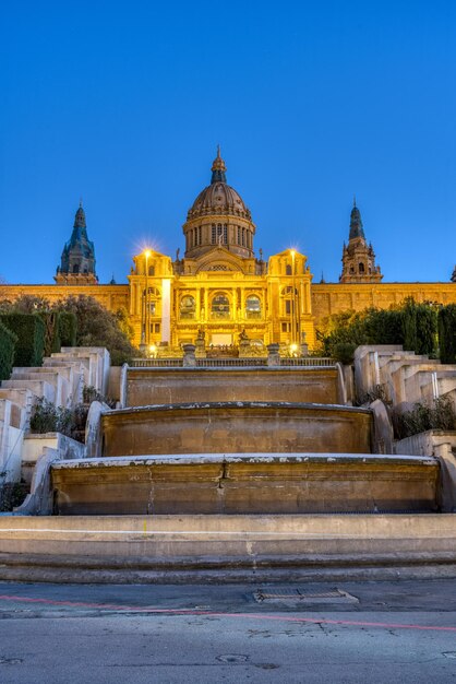 Foto o palácio nacional na montanha montjuic, em barcelona, iluminado ao anoitecer