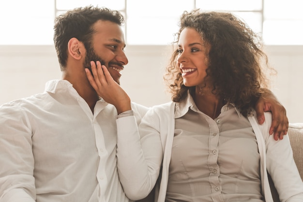 O par afro-americano bonito está abraçando e está sorrindo.