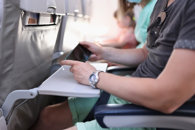 O passageiro do avião fica parado e segura o telefone nas mãos.