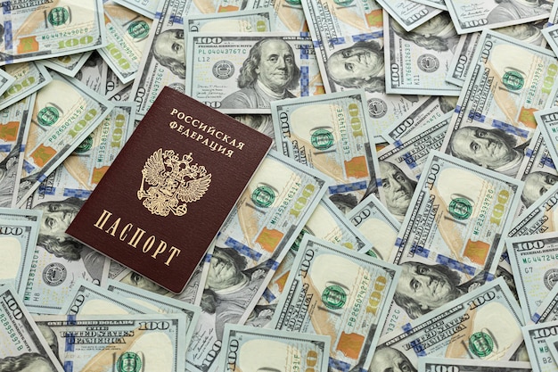 O passaporte está deitado em uma pilha de notas de cem dólares Documentos e dinheiro