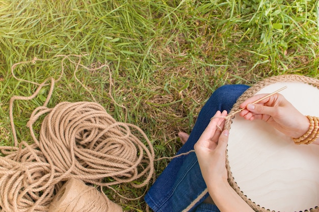 O passatempo de trabalho manual mulher está fazendo uma cesta de crochê com um cordão grosso de materiais ecológicos