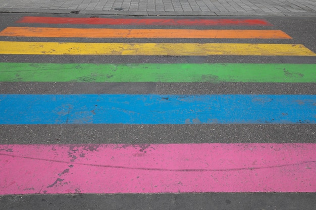 O pedestre lgbt pinta as cores da rua da cidade cruzando a marcação do caminho de pedestres na bandeira gay lésbica do arco-íris colorido LGBT na cidade