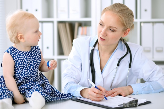 O pediatra está cuidando do bebê no hospital A menina está sendo examinada pelo médico com estetoscópio Seguro de saúde e conceito de ajuda