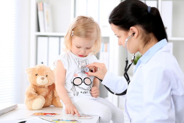 O pediatra está cuidando do bebê no hospital A menina está sendo examinada pelo médico com estetoscópio Seguro de saúde e conceito de ajuda