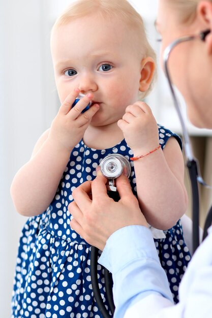 O pediatra está cuidando do bebê no hospital A menina está sendo examinada pelo médico com estetoscópio Seguro de saúde e conceito de ajuda