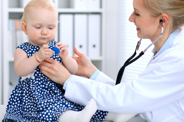 O pediatra está cuidando do bebê no hospital A menina está sendo examinada pelo médico com estetoscópio Seguro de saúde e conceito de ajuda