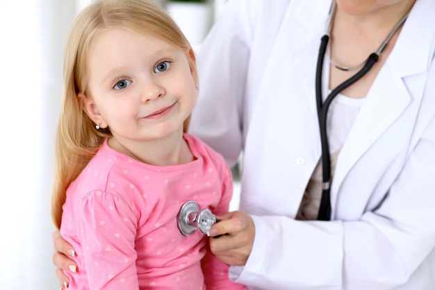 O pediatra está cuidando do bebê no hospital A menina está sendo examinada pelo médico pelo estetoscópio Seguro de saúde e conceito de ajuda