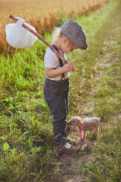 O pequeno viajante encontrou um leitão no campo. Foto retrô.