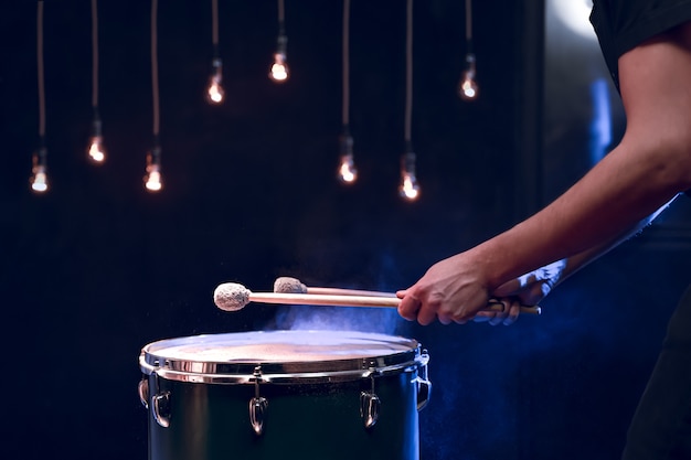 O percussionista toca paus no chão em uma sala escura e com bela iluminação. conceito de concerto e performance.