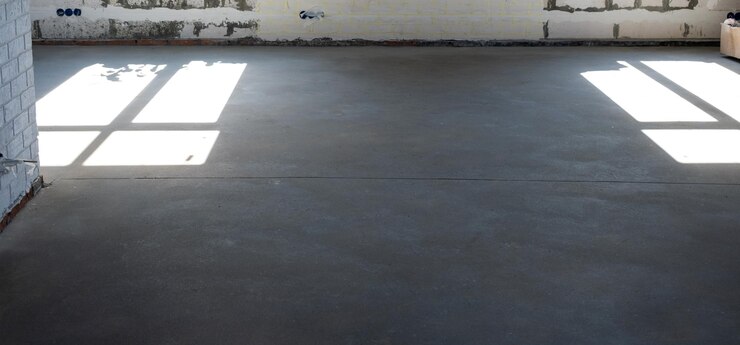 Foto o piso áspero nivelado em uma casa em construção com uma mesa de cimento semi-seca é uma superfície lisa com luz das janelas