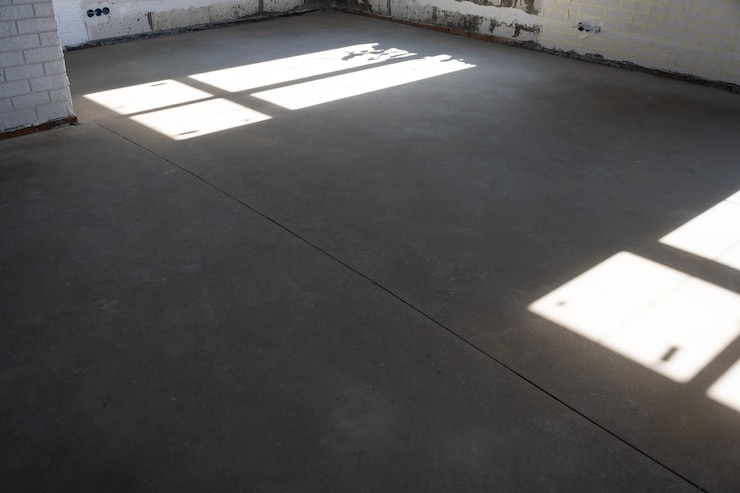 Foto o piso áspero nivelado em uma casa em construção com uma mesa de cimento semi-seca é uma superfície lisa com luz das janelas