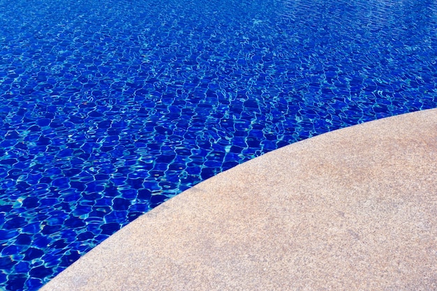 O piso de ladrilhos azuis sob a água limpa no fundo da piscina Superfície da piscina com ladrilhos de mosaico em azul