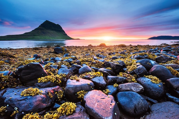 O pitoresco pôr do sol sobre paisagens e cachoeiras. Montanha Kirkjufell, Islândia