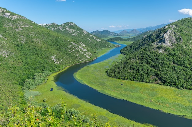 O pitoresco rio sinuoso corre entre montanhas verdes