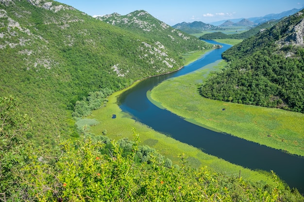 O pitoresco rio sinuoso corre entre montanhas verdes.