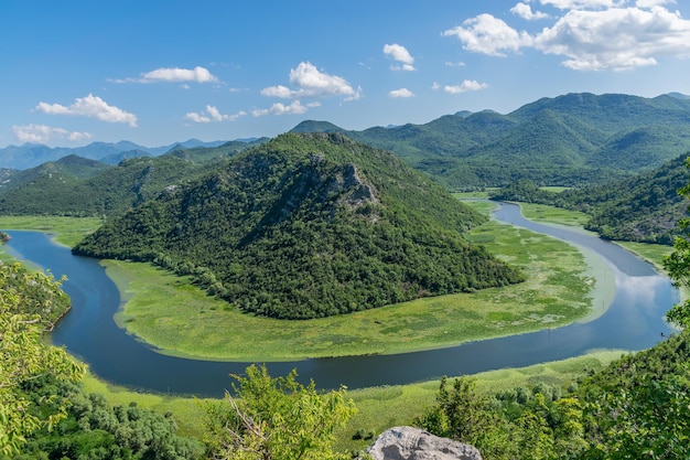 O pitoresco rio sinuoso flui entre montanhas verdes