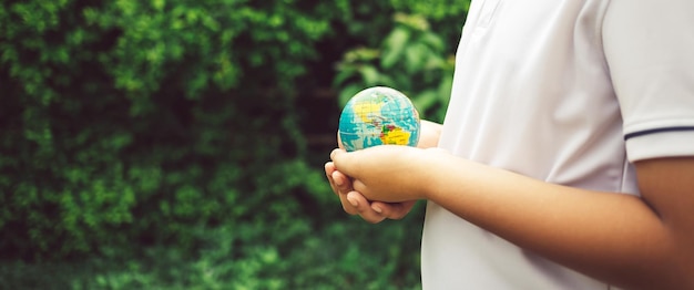 O planeta terra nas mãos do menino salva e protege o fundo da natureza mundial Ambiental