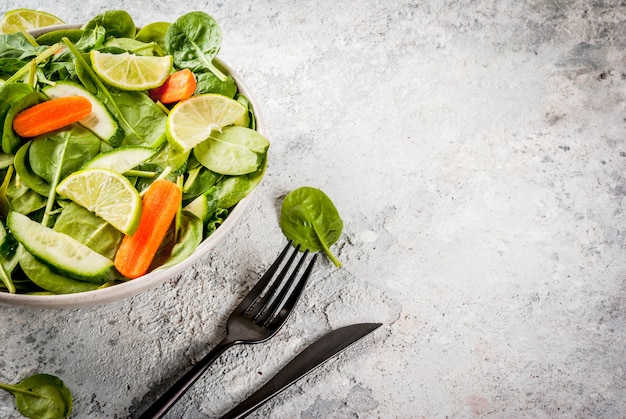 O plano da dieta perde o conceito, salada de legumes fresca com garfo, faca, espaço da cópia da mesa de pedra cinza