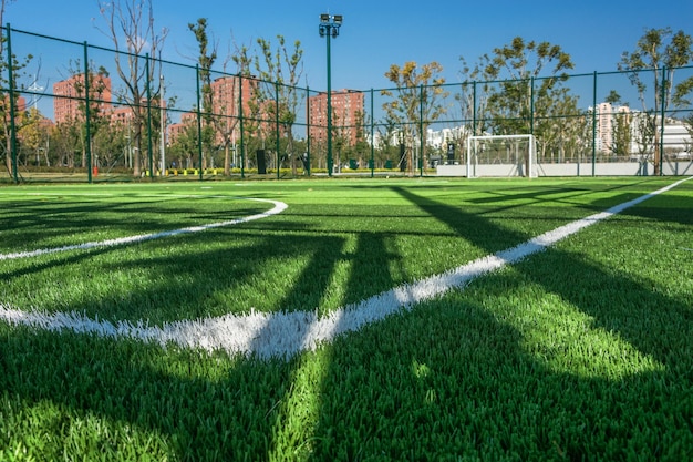 O playground esportivo no parque com grama artificial e uma rede esticada sobre um fundo de árvores verdes