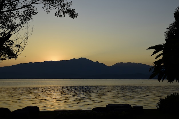 Foto o por do sol com a montanha e o lago em kwan phayao.