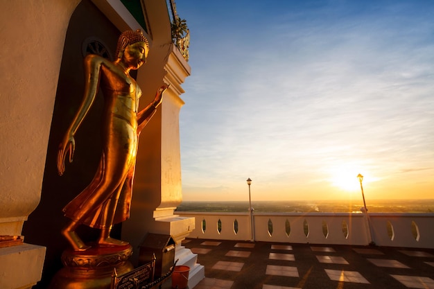 O pôr do sol da paisagem com o nome da imagem de buda de ouro em pé é wat sra song pee nong em phitsanulok