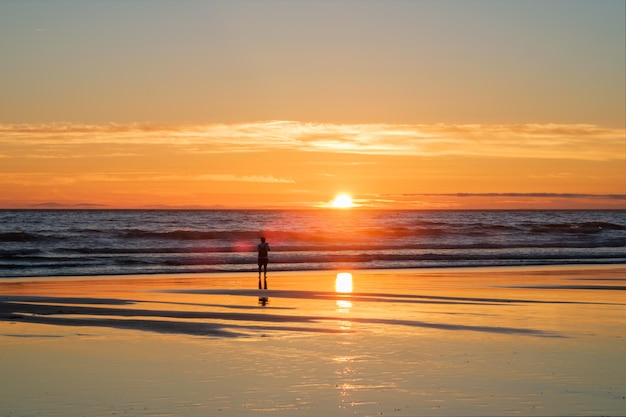 O pôr-do-sol do Oceano Atlântico com ondas ondulantes na praia de fonte da telha, Portugal