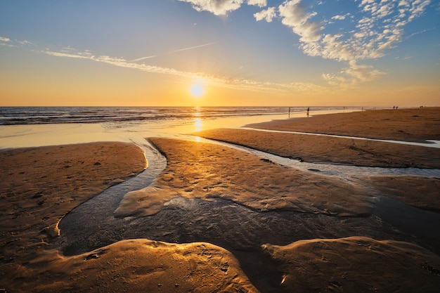 O pôr-do-sol do Oceano Atlântico com ondas ondulantes na praia de fonte da telha, Portugal