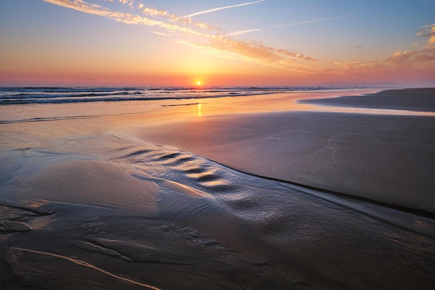 Foto o pôr-do-sol do oceano atlântico com ondas ondulantes na praia de fonte da telha, portugal