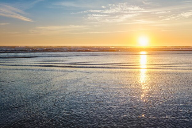 O pôr-do-sol do Oceano Atlântico com ondas ondulantes na praia de fonte da telha, Portugal