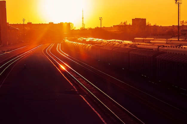 O pôr do sol escarlate na estação a plataforma e os carros
