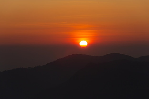 O pôr do sol no alto das montanhas antes da silhueta negra das montanhas